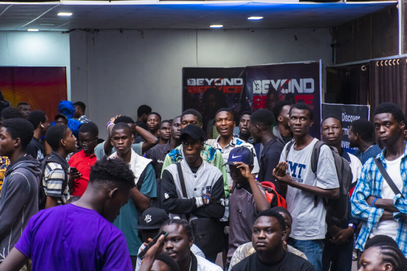 A group of people are gathered in a room, some of them are holding cell phones.